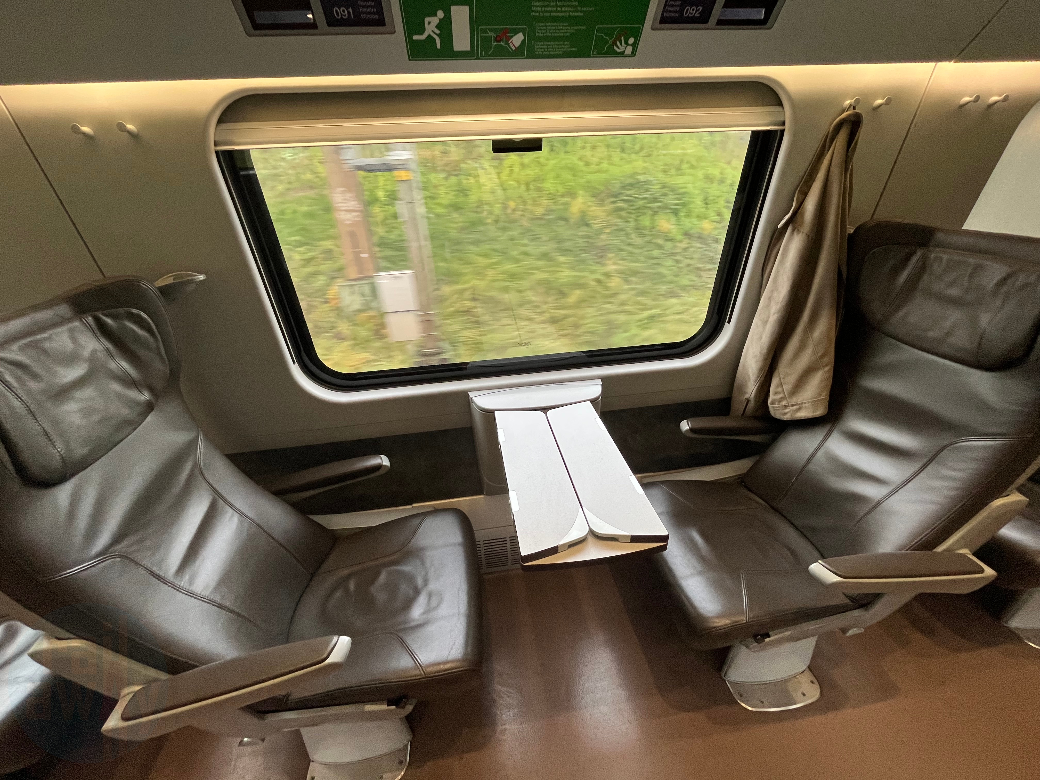 Two style brown leather seats in the First Class coach, one facing the other with a foldable table